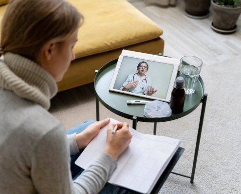 Patient at home taking notes during a video visit with a doctor